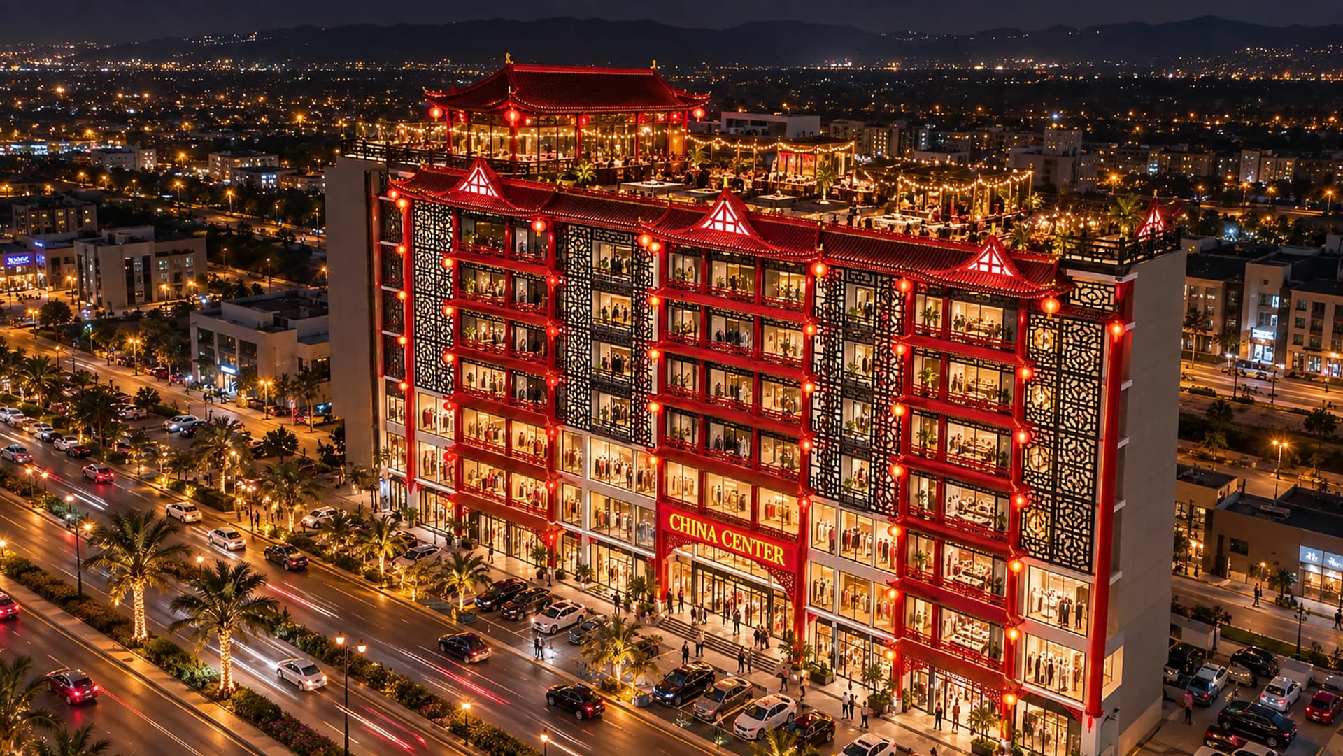 Night aerial view of China Center lit up on the boulevard, the rooftop pavilion glowing and the city lights beyond